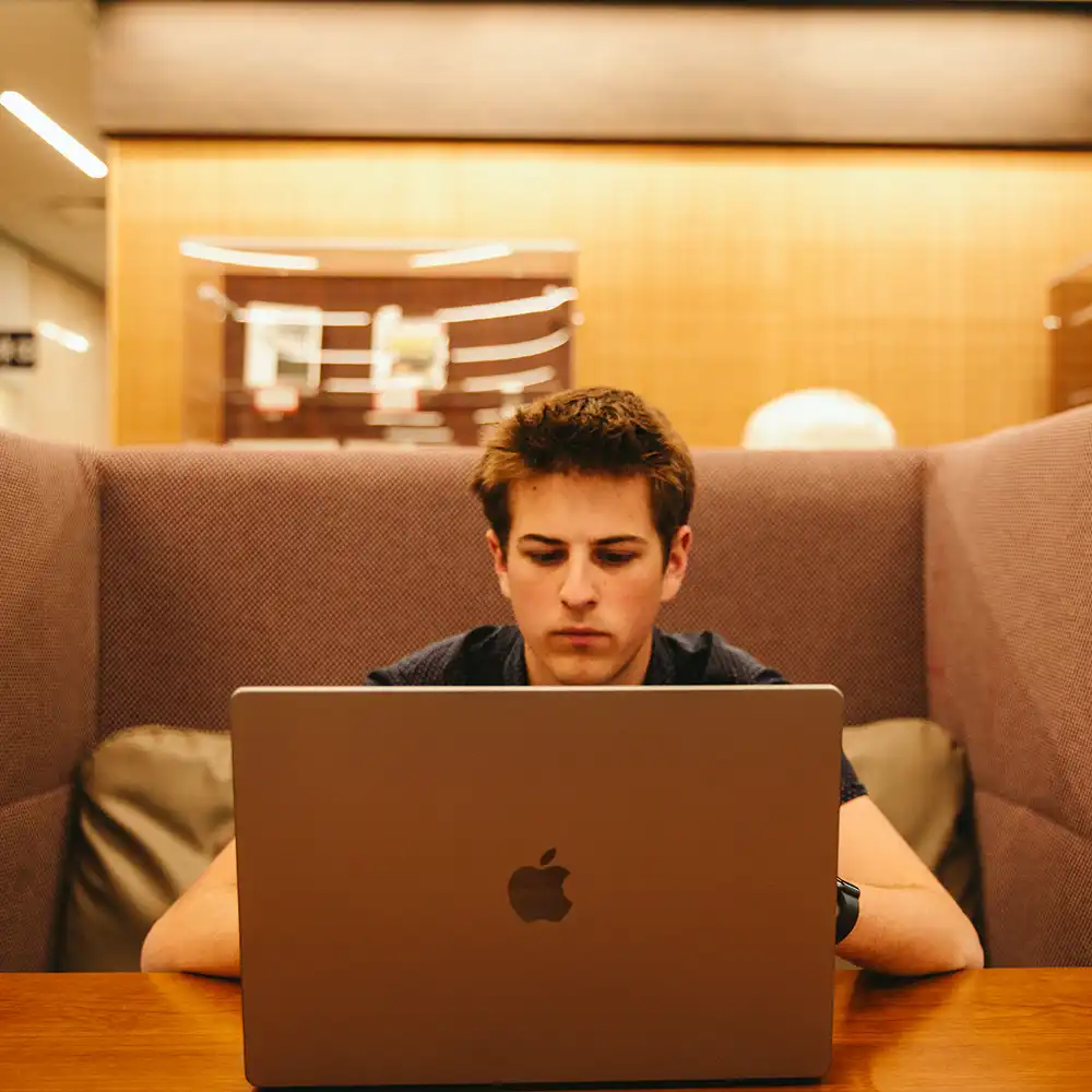 SHSU Student working in a library on a laptop.