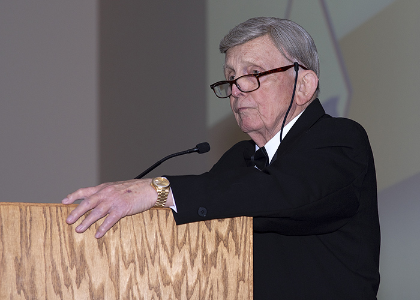 Speaker at podium looking thoughtfully at audience