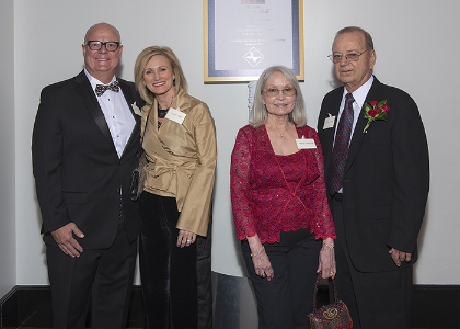 Hall and others pose in front of award