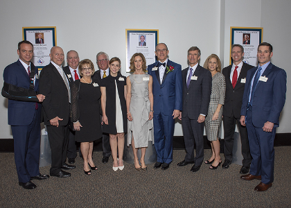 A dozen people pose in front of awards