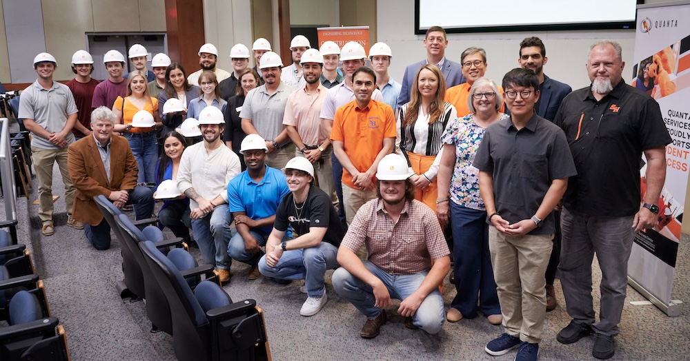 Michelle Boyd (middle row, third from right) and John WeHunt (bottom row, first on left) take a group photo with the hard hat recipients and the leaders of the construction management program.