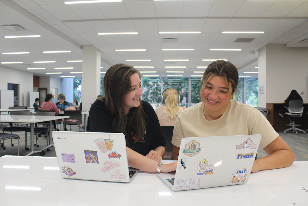 Two students sitting at a table with laptops