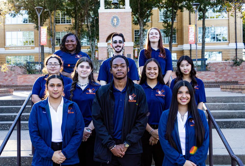 Members of SGA stand in front of the clock tower poised in their blue shirts and jackets.