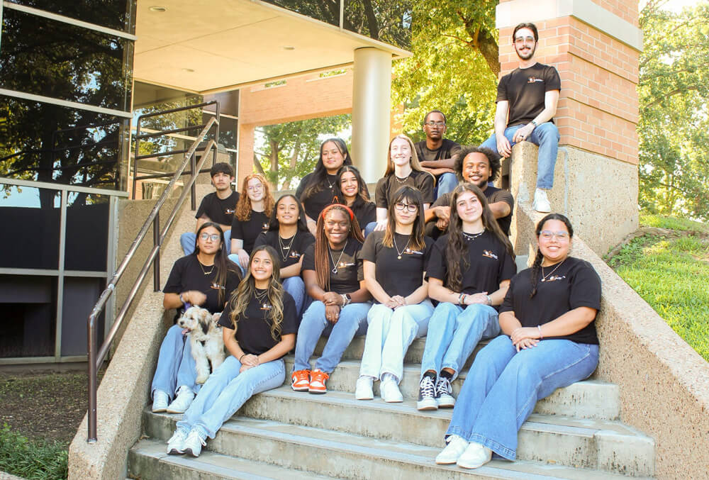 Members of SGA sit on steps in their black shirts.