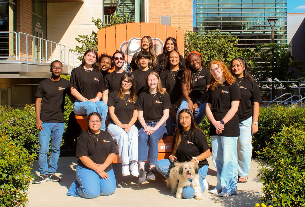 Members of SGA sit on the large orange Sammy chair in front of the LSC.