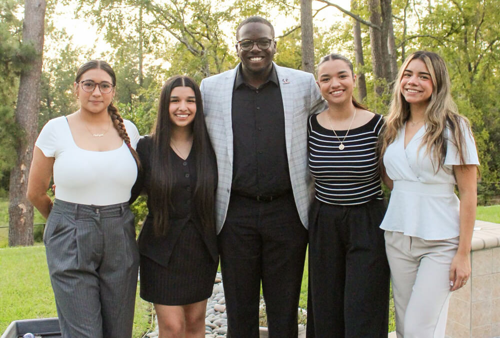 Five people stand smiling.