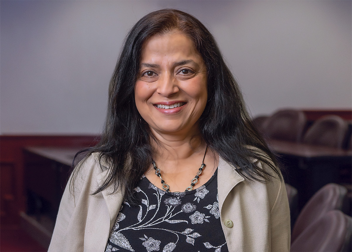 Sharmistha Self leans on an auditorium chair and smiles for the camera.