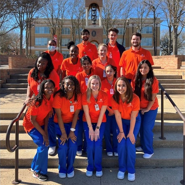 Sam Houston State University's School of Nursing Students grouped together for a photo on some stairs in front of the belltower